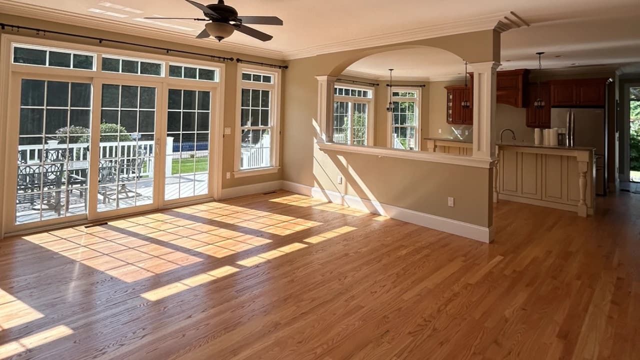 Open-concept hardwood install across kitchen, dining, and living room with French doors and ceiling fan